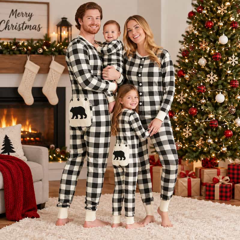 A family of four wearing matching black and white buffalo plaid Christmas pajamas stands in a cozy living room decorated for Christmas, with a fireplace, stockings, and a decorated tree in the background.