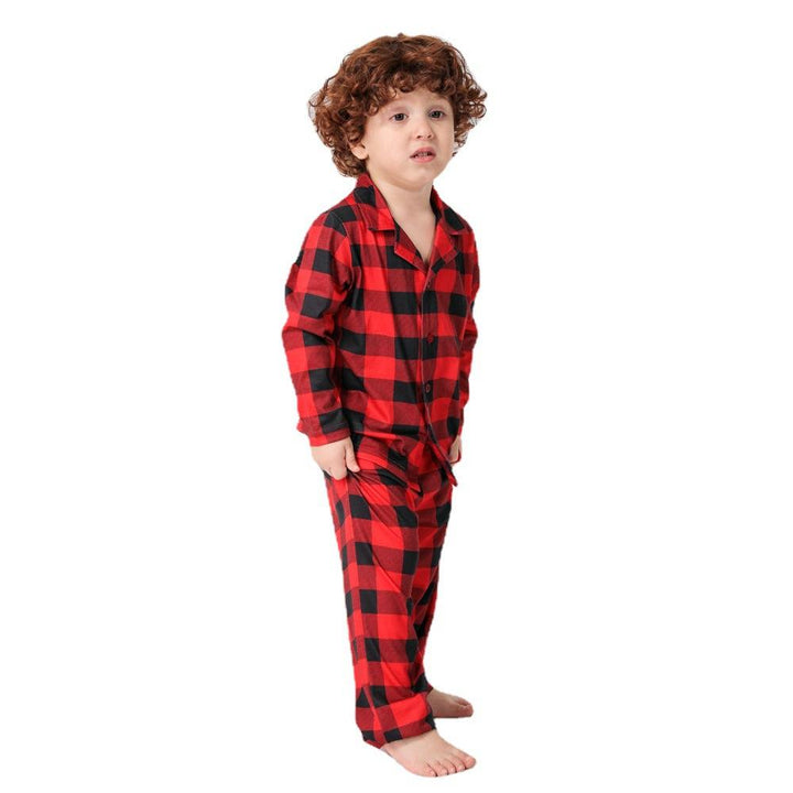 Child wearing red and black checkered pajamas on a white background