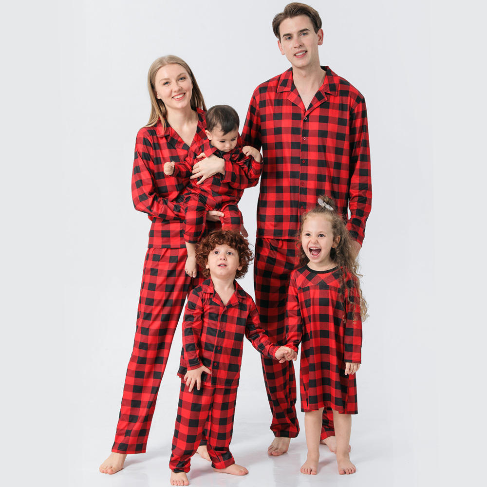 Family of four wearing red and black plaid pajamas on a white background